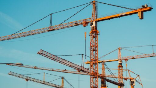 Construction worker using a digital timesheet app on a tablet, tracking hours and project progress on a busy construction site.