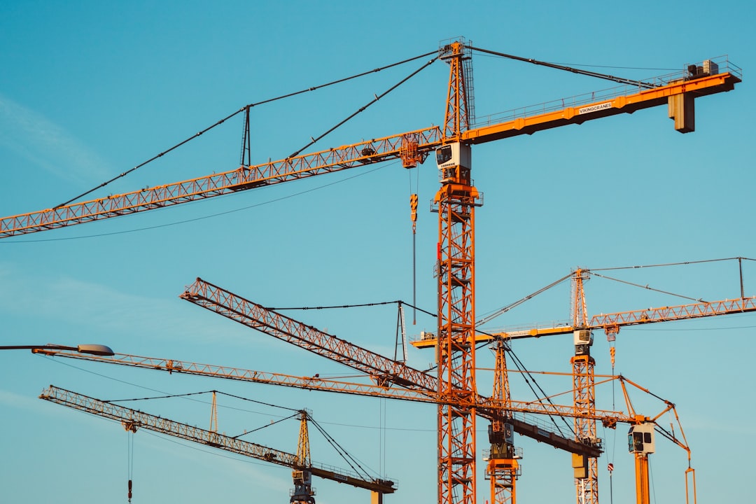 Construction worker using a digital timesheet app on a tablet, tracking hours and project progress on a busy construction site.